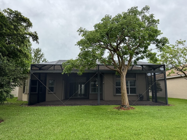 10469 Whitewind Cir, Boynton Beach, FL 33473 - rear view of property featuring glass enclosure, a lawn, a patio area, and stucco siding
