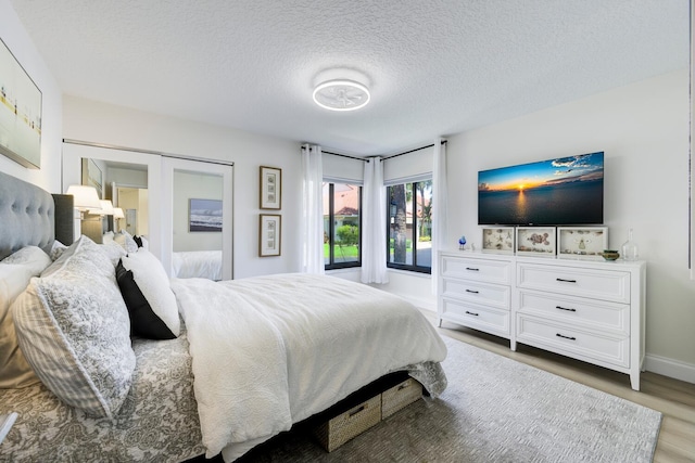 508 Sea Oats Dr Unit A-1, Juno Beach, FL 33408 - bedroom with light wood-style flooring, a textured ceiling, and baseboards