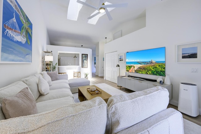 508 Sea Oats Dr Unit A-1, Juno Beach, FL 33408 - living area with a skylight, wood finished floors, high vaulted ceiling, a ceiling fan, and baseboards