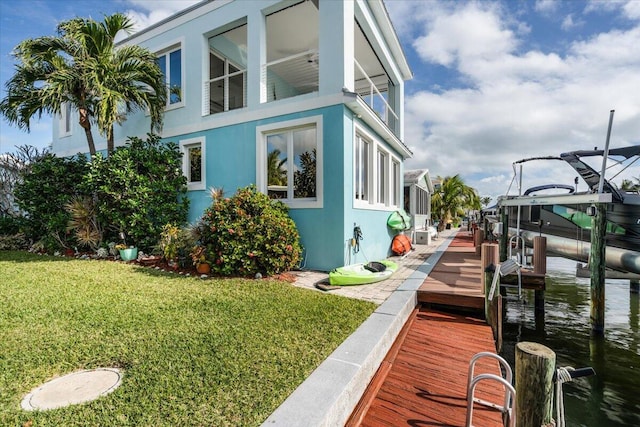 10851 S Ocean Dr Unit 84, Jensen Beach, FL 34957 - view of home's exterior featuring boat lift, a boat dock, stucco siding, and a yard