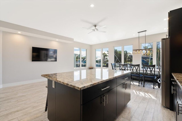 10851 S Ocean Dr Unit 84, Jensen Beach, FL 34957 - kitchen featuring light wood-type flooring, recessed lighting, a ceiling fan, a kitchen island, and light stone countertops