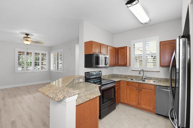1595 SE Pomeroy St, Stuart, FL 34997 - kitchen featuring appliances with stainless steel finishes, a sink, a peninsula, ceiling fan, and light stone counters