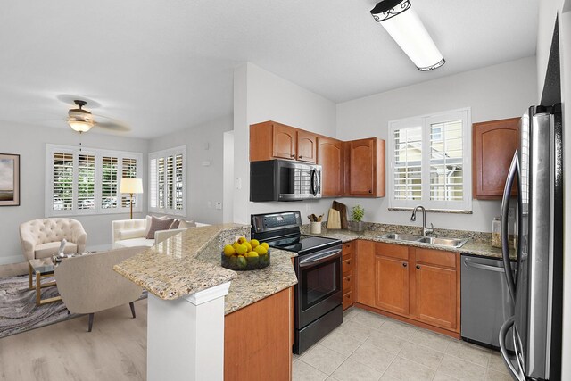 1595 SE Pomeroy St, Stuart, FL 34997 - kitchen featuring appliances with stainless steel finishes, a sink, open floor plan, a peninsula, and light stone counters