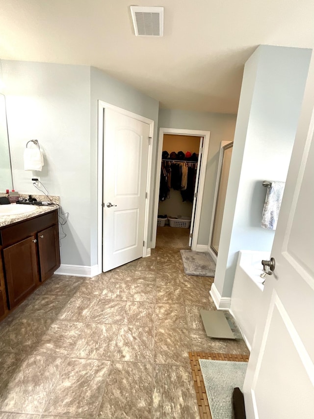 1206 SW Bargello Ave SW, Port Saint Lucie, FL 34953 - bathroom featuring vanity, a spacious closet, a garden tub, a shower stall, and baseboards