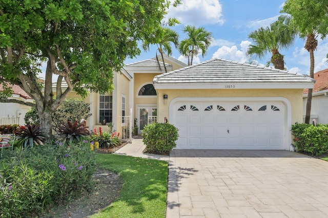 13853 Palm Grove Pl, West Palm Beach, FL 33418 - view of front of house featuring stucco siding, decorative driveway, a garage, and a tiled roof