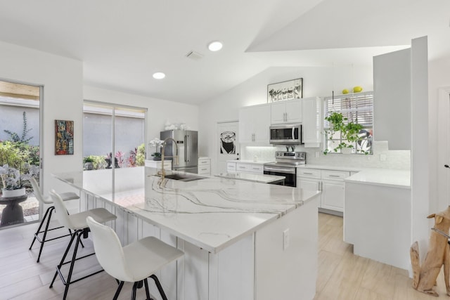 13853 Palm Grove Pl, West Palm Beach, FL 33418 - kitchen featuring stainless steel appliances, lofted ceiling, a breakfast bar area, backsplash, and white cabinetry