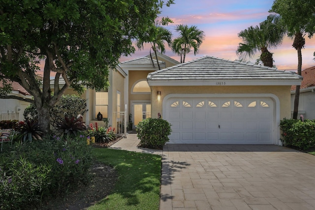 13853 Palm Grove Pl, West Palm Beach, FL 33418 - view of front of home featuring stucco siding, decorative driveway, and an attached garage