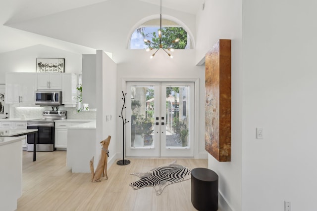 13853 Palm Grove Pl, West Palm Beach, FL 33418 - entrance foyer featuring a chandelier, french doors, high vaulted ceiling, and light wood-style flooring