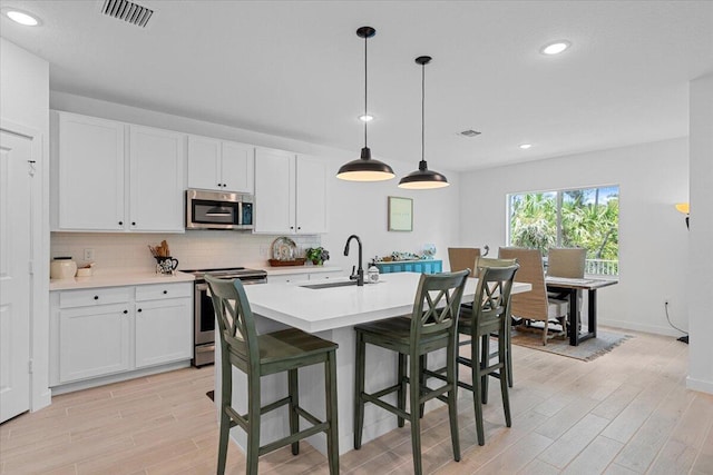 821 NE Trailside Run, Port Saint Lucie, FL 34983 - kitchen featuring appliances with stainless steel finishes, a sink, backsplash, light countertops, and light wood-style flooring