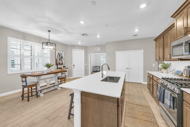 1246 Tangled Orchard Trce, Loxahatchee, FL 33470 - kitchen featuring stainless steel appliances, a center island with sink, a sink, baseboards, and light countertops