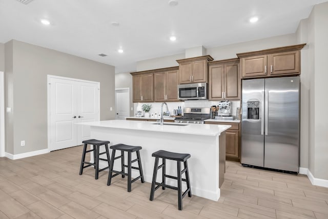 1246 Tangled Orchard Trce, Loxahatchee, FL 33470 - kitchen featuring stainless steel appliances, a sink, wood tiled floors, a kitchen island with sink, and a kitchen breakfast bar