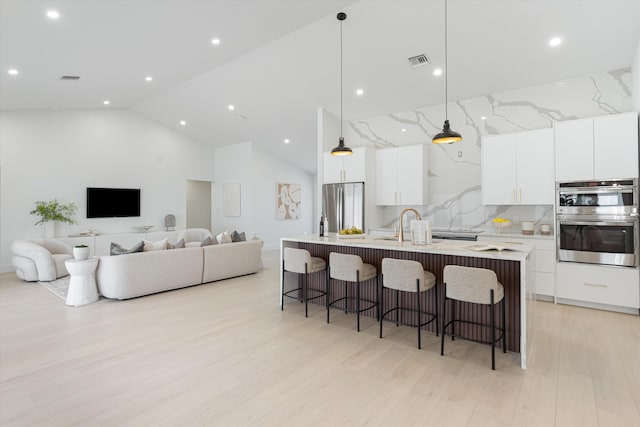 3099 NW 25th Way, Boca Raton, FL 33434 - kitchen with appliances with stainless steel finishes, high vaulted ceiling, an island with sink, a breakfast bar, and white cabinets