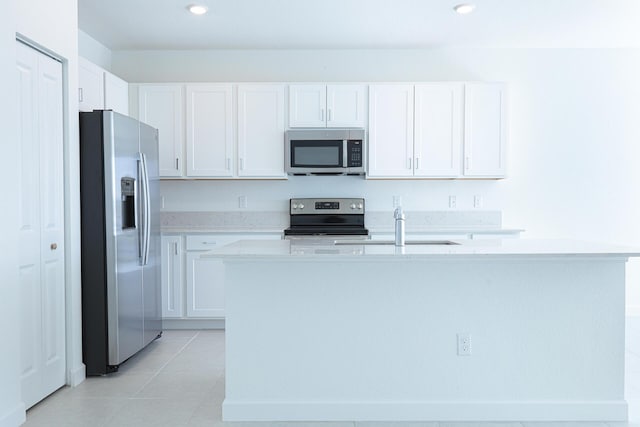 242 SE Woodbark St, Port Saint Lucie, FL 34984 - kitchen with stainless steel appliances, white cabinets, light countertops, a kitchen island with sink, and light tile patterned floors