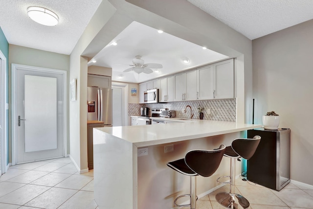 2731 NE 14th Cswy Unit 702, Pompano Beach, FL 33062 - kitchen featuring stainless steel appliances, a sink, light countertops, light tile patterned flooring, and a textured ceiling