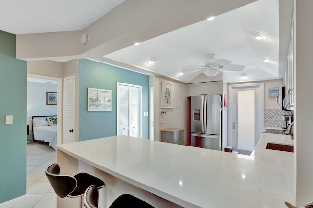 2731 NE 14th Cswy Unit 702, Pompano Beach, FL 33062 - kitchen featuring stainless steel fridge, a peninsula, light tile patterned flooring, ceiling fan, and a kitchen breakfast bar