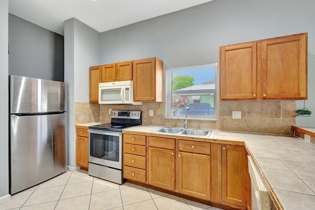 332 S E St, Lake Worth Beach, FL 33460 - kitchen featuring appliances with stainless steel finishes, tile countertops, a sink, decorative backsplash, and light tile patterned flooring