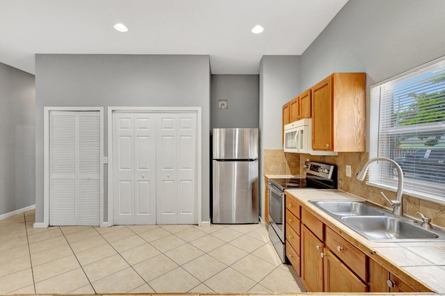 332 S E St, Lake Worth Beach, FL 33460 - kitchen featuring appliances with stainless steel finishes, a sink, tile counters, light tile patterned floors, and brown cabinets