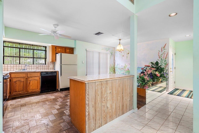 4744 Dolphin Dr, Lake Worth, FL 33463 - kitchen featuring black dishwasher, freestanding refrigerator, a sink, light countertops, and brown cabinetry
