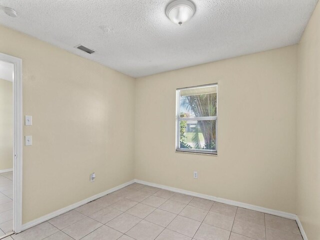 526 NW Kingston St, Port Saint Lucie, FL 34983 - empty room featuring a textured ceiling, light tile patterned flooring, and baseboards