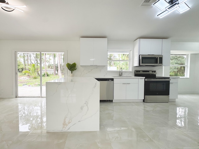 15809 85th Rd N, The Acreage, FL 33470 - kitchen featuring stainless steel appliances, a sink, light stone counters, white cabinetry, and light marble finish flooring