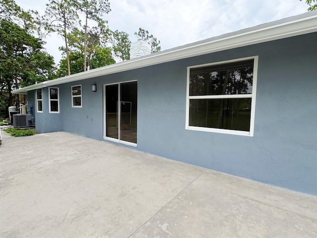 15809 85th Rd N, The Acreage, FL 33470 - back of property featuring a patio area, central air condition unit, stucco siding, and a chimney