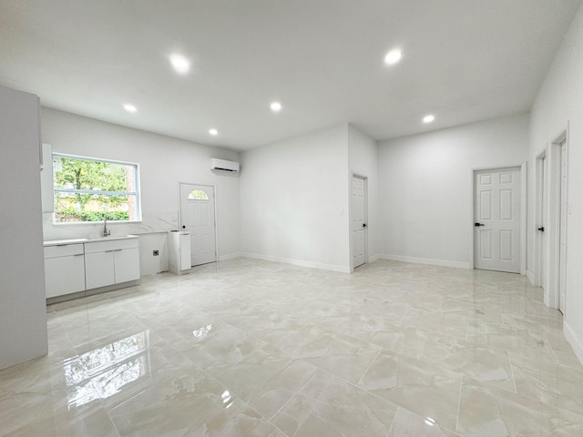 15809 85th Rd N, The Acreage, FL 33470 - unfurnished living room with a wall mounted air conditioner, recessed lighting, light marble finish floors, baseboards, and a sink
