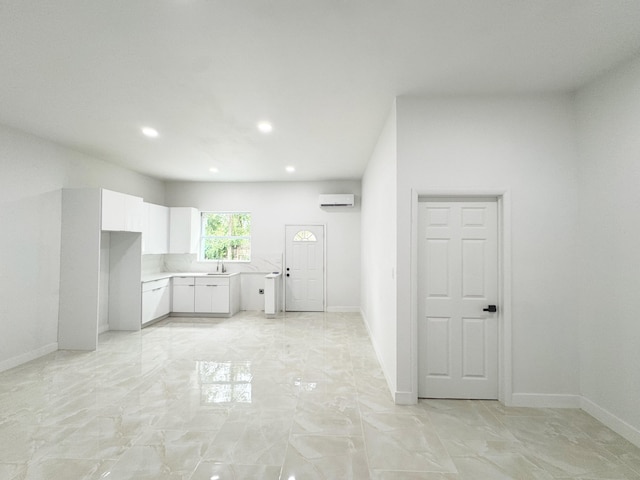15809 85th Rd N, The Acreage, FL 33470 - kitchen with white cabinets, light marble finish floors, light countertops, an AC wall unit, and baseboards