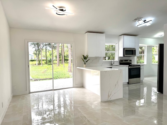 15809 85th Rd N, The Acreage, FL 33470 - kitchen with stainless steel appliances, light marble finish floors, light stone countertops, white cabinetry, and baseboards