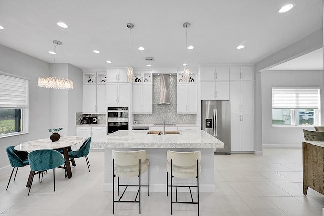5452 Macoon Way, Westlake, FL 33470 - kitchen featuring stainless steel appliances, wall chimney range hood, an island with sink, tasteful backsplash, and baseboards