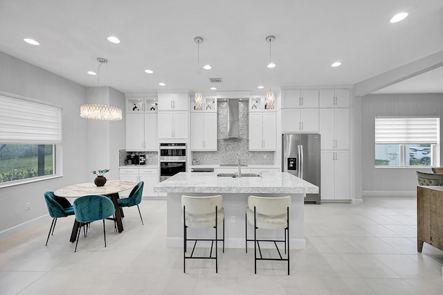 5452 Macoon Way, Westlake, FL 33470 - kitchen with stainless steel appliances, wall chimney range hood, an island with sink, decorative backsplash, and a sink