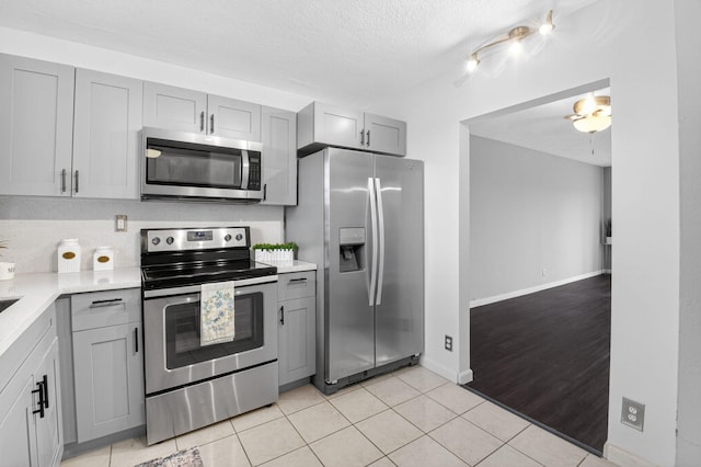 9370 SW 8th St Unit 410, Boca Raton, FL 33428 - kitchen with appliances with stainless steel finishes, gray cabinetry, light countertops, a textured ceiling, and light tile patterned floors