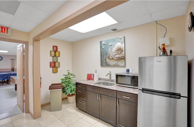 2768 Carambola Cir S Unit 301, Coconut Creek, FL 33066 - kitchen with appliances with stainless steel finishes, a paneled ceiling, a sink, dark brown cabinetry, and light tile patterned floors