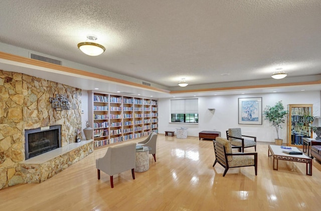 2768 Carambola Cir S Unit 301, Coconut Creek, FL 33066 - living room featuring a textured ceiling, wood finished floors, and a stone fireplace
