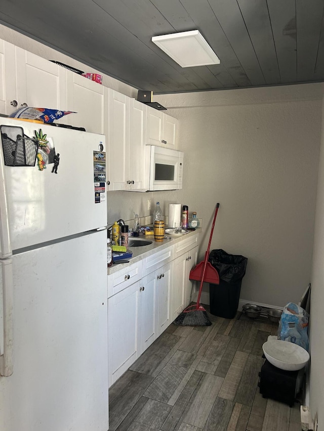 617 54th St, West Palm Beach, FL 33407 - kitchen featuring white appliances, light countertops, white cabinetry, dark wood-type flooring, and a sink