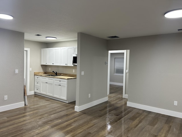 617 54th St, West Palm Beach, FL 33407 - kitchen with dark wood-style flooring, baseboards, a sink, white cabinetry, and light countertops