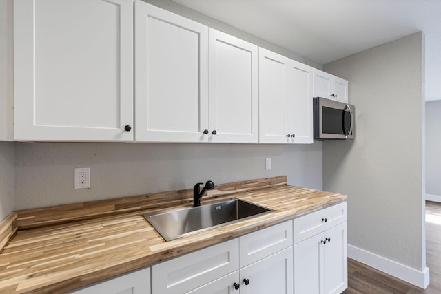 617 54th St, West Palm Beach, FL 33407 - kitchen featuring butcher block countertops, stainless steel microwave, baseboards, a sink, and dark wood-style floors