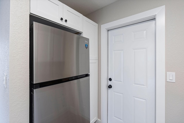 617 54th St, West Palm Beach, FL 33407 - kitchen featuring freestanding refrigerator, white cabinets, and a textured wall
