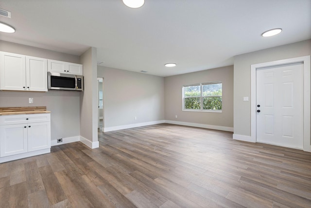 617 54th St, West Palm Beach, FL 33407 - kitchen featuring stainless steel microwave, white cabinets, wood finished floors, and baseboards