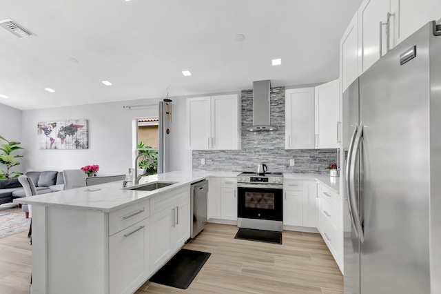 9640 Cherry Blossom Ct, Boynton Beach, FL 33437 - kitchen featuring appliances with stainless steel finishes, wall chimney exhaust hood, a sink, a peninsula, and light stone countertops