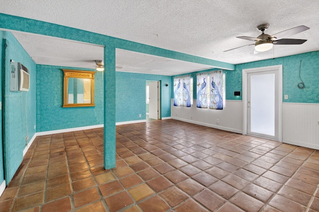 1115 S Seacrest Blvd, Boynton Beach, FL 33435 - unfurnished living room with ceiling fan, a textured ceiling, tile patterned flooring, a wall unit AC, and wainscoting