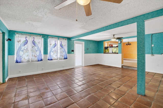1115 S Seacrest Blvd, Boynton Beach, FL 33435 - empty room featuring a ceiling fan, a textured ceiling, wainscoting, and tile patterned floors