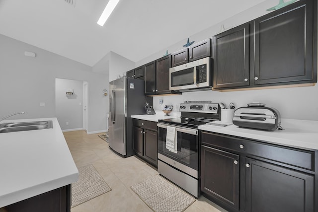 191 SW Glenwood Dr, Port Saint Lucie, FL 34984 - kitchen with stainless steel appliances, light countertops, a sink, lofted ceiling, and light tile patterned floors