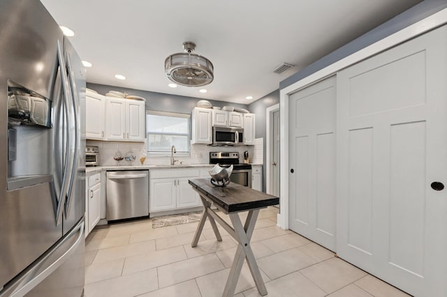 1056 SW 27th Ave, Boynton Beach, FL 33426 - kitchen featuring appliances with stainless steel finishes, light countertops, decorative backsplash, white cabinetry, and recessed lighting