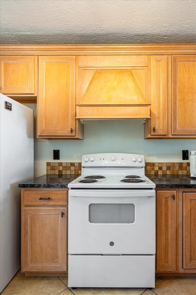 1950 SW Palm City Rd Unit 5109, Stuart, FL 34994 - kitchen featuring electric stove, freestanding refrigerator, custom exhaust hood, and dark stone countertops