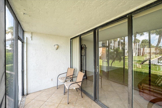 1950 SW Palm City Rd Unit 5109, Stuart, FL 34994 - unfurnished sunroom with a textured wall, plenty of natural light, a textured ceiling, expansive windows, and tile patterned flooring