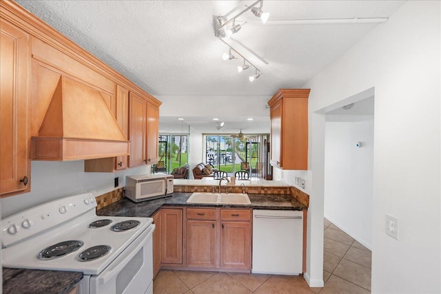 1950 SW Palm City Rd Unit 5109, Stuart, FL 34994 - kitchen with white appliances, premium range hood, light tile patterned floors, dark countertops, and a textured ceiling
