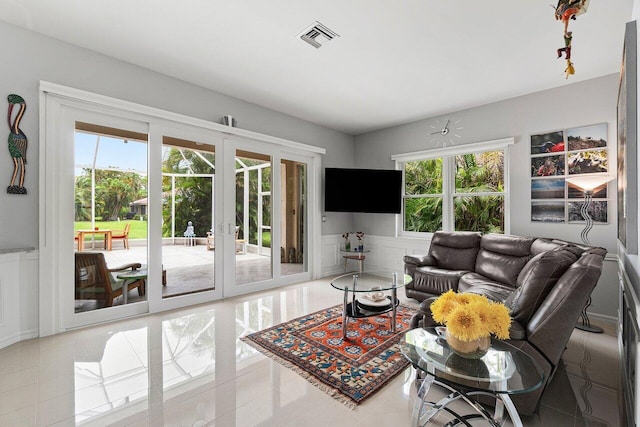 137 N Lakeshore Dr, Hypoluxo, FL 33462 - tiled living room with healthy amount of natural light, a wainscoted wall, and a decorative wall