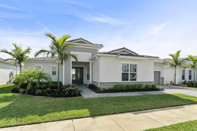10647 SW Vineyard Dr, Port Saint Lucie, FL 34987 - view of front of home featuring french doors, decorative driveway, a front yard, an attached garage, and stucco siding