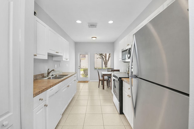 2186 SE Destin Dr, Port Saint Lucie, FL 34952 - kitchen featuring stainless steel appliances, a sink, white cabinets, light tile patterned floors, and recessed lighting