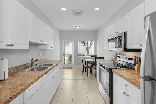 2186 SE Destin Dr, Port Saint Lucie, FL 34952 - kitchen featuring stainless steel appliances, a sink, light tile patterned floors, recessed lighting, and white cabinetry